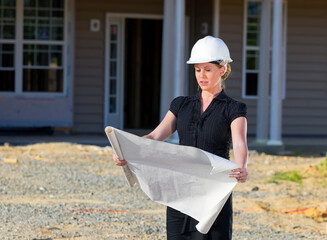 Female Architect On Construction Site Looking Over Blueprints