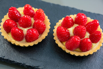 Artisanal baked small tart with cream and fresh ripe red raspberry