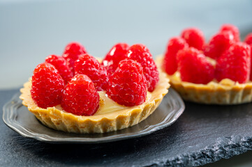 Artisanal baked small tart with cream and fresh ripe red raspberry