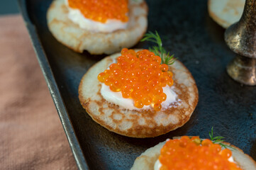 Tasty appetizer for dinner, small pancakes bliny with red fish caviar and sour cream