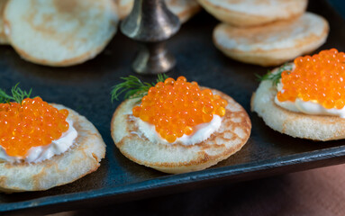 Tasty appetizer for dinner, small pancakes bliny with red fish caviar and sour cream