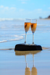 Two glasses of rose champagne or cava sparkling wine served on white sandy tropical beach and blue ocean water, romantic vacation, winter sun on Fuerteventura, Canary, Spain