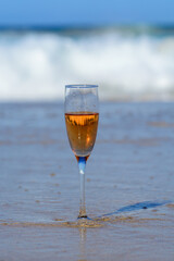 One glass of rose champagne or cava sparkling wine served on white sandy beach and blue ocean water, romantic vacation, winter sun on Fuerteventura, Canary, Spain