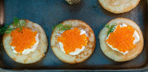 Tasty appetizer for dinner, small pancakes bliny with red fish caviar and sour cream