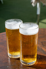 Fresh draught lager or IPA beer is glass served in outdoor cafe close up, pint of beer close up