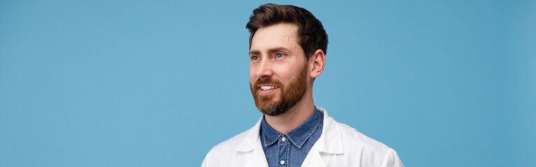 Fototapeta premium Portrait of handsome professional doctor looking away standing over blue studio background