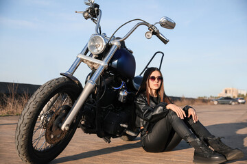 Beautiful woman sitting near motorcycle on sunny day