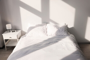 Fototapeta na wymiar White soft pillows on bed in room