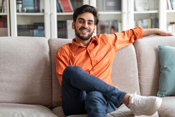 Cool middle eastern guy chilling at home, smiling at camera