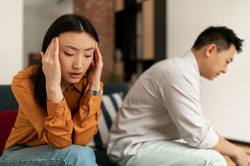 Naklejka na ściany i meble Unhappy young asian woman crying after quarrel with husband, korean couple experiencing difficulties in relationships