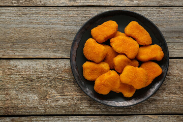 Tasty chicken nuggets on wooden table, top view. Space for text