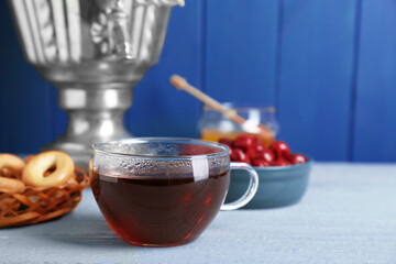 Glass cup of aromatic tea on light blue wooden table