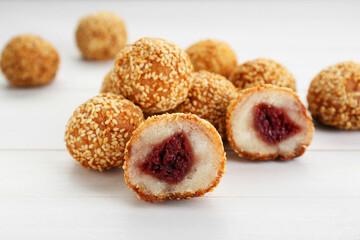 Delicious sesame balls with red bean paste on white wooden table, closeup
