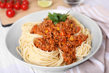 Tasty dish with fried minced meat, spaghetti, carrot and corn on white wooden table, closeup