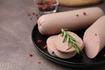 Delicious liver sausages with rosemary on brown textured table, closeup. Space for text