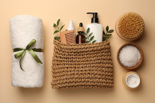 Preparation for spa. Compact toiletry bag with different cosmetic products, sea salt and towel on beige background, flat lay