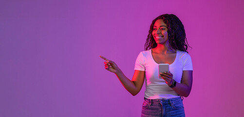 Special Offer. Smiling Black Woman Holding Smartphone And Pointing At Copy Space
