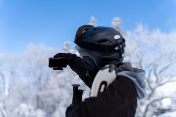 Fototapeta na wymiar Young Asian man using mobile phone taking selfie during skiing on snowy mountain slope at in ski resort. Handsome guy enjoy winter activity lifestyle extreme sport training freeride ski on vacation.
