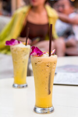 Summer fresh drink concept. Passion Fruit shake or frappe with the brown straw on the white table in a cafe.