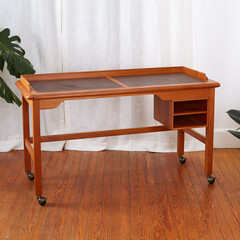 Vintage leather top writing desk, interior view in front of luxurious curtain with houseplants. 