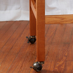 Vintage writing desk, interior view in front of a luxurious curtain Close-up detail of legs with casters.