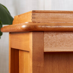 Vintage leather top writing desk, interior view in front of a luxurious curtain with houseplants. Close-up detail of finger joinery