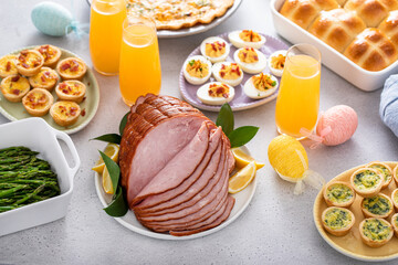Easter brunch table with ham, quiche, hot cross buns