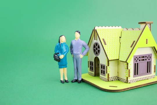 a pair of miniature people with a model house. the concept of home ownership. real estate property concept