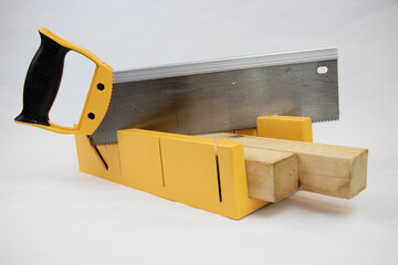 yellow hand saw and hard plastic miter box for hobby in home workshop