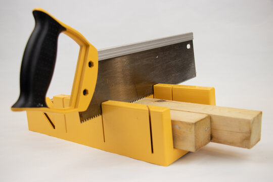 yellow hand saw and hard plastic miter box for hobby in home workshop