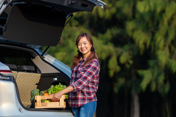 Asian farmer is delivering freshly harvest of organics vegetable box into the customer trunk car...