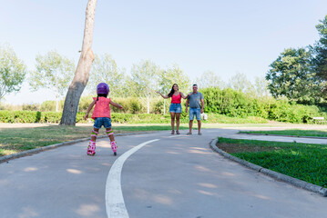 Obraz premium Girl with her parents roller skating outdoors in the park.