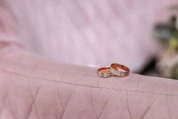 Two gold wedding rings. Close-up of gold wedding rings on a pink soft surface.