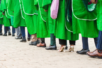 Line up of university graduating students wearing their green graduation outfit and marching...
