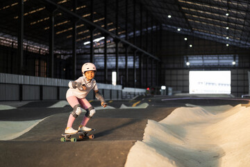 asian child surf skater or kid girl fun playing skateboard or ride surfskate in indoor pump track in skate park by extreme sports surfing to wear helmet elbow pads wrist knee support for body safety © kornnphoto
