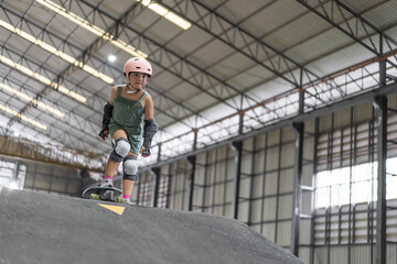 asian child skater or kid girl fun playing skateboard or ride surf skate to start on wave ramp pump track in skate park by extreme sports surfing to wear helmet elbow wrist knee guard for body safety