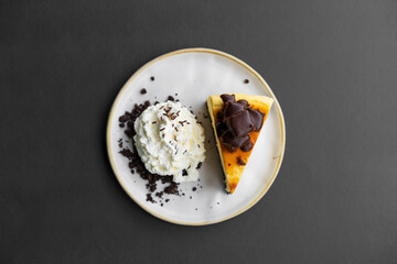 chocolate brownie cheesecake with whipped cream on white dish or plate and black table background by top view for sweet dessert or snack and food in bakery coffee shop or cafe restaurant and isolated