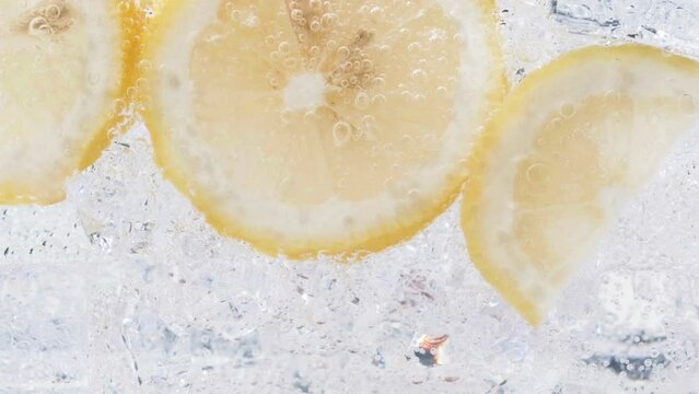 Soda water with ice cubes and sliced lemon slow motion video.