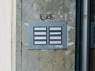 Dirty doorbell panel without names. Template with blank spaces next to a door. Anonymous apartments in a big city. Eight flats in a house.