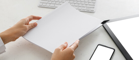 Woman holding blank paper sheets at workplace in office