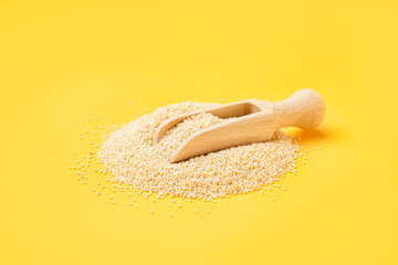 Wooden scoop of amaranth seeds on yellow background