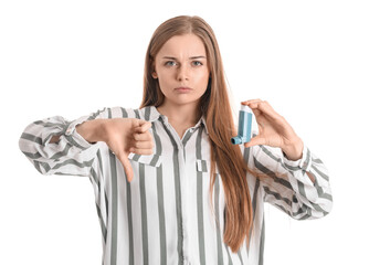 Young woman with inhaler showing thumb-down on white background