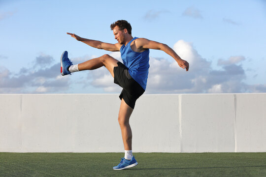Runner man getting ready to run doing warm-up dynamic leg stretch exercises routine, Male athlete stretching lower body hamstring muscles before going running outside in summer outdoors.