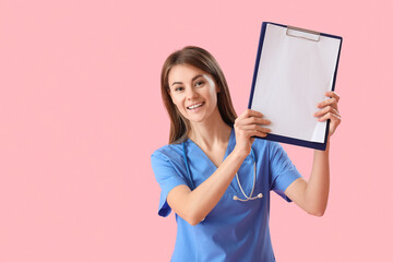 Female medical intern with clipboard on pink background