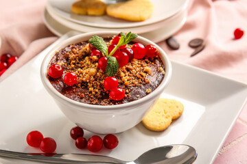 Bowl of delicious chocolate pudding with cranberry on pink tile table