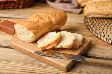 Cutting board with sliced baguette on wooden table