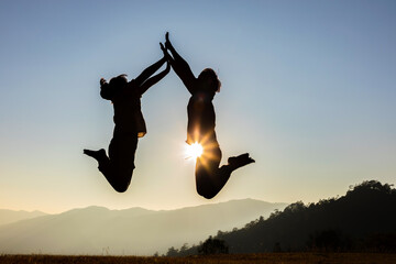 happy couple jumping on mountain meadow sunset background