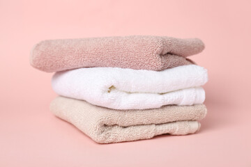 Stack of clean towels on pink background
