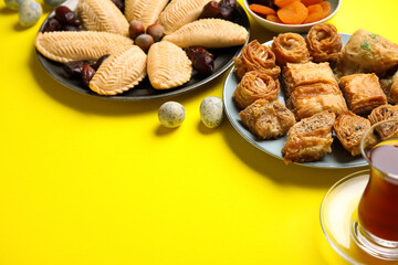 Plates with treats and eggs on yellow background, closeup. Novruz Bayram celebration
