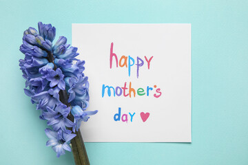 Card with text HAPPY MOTHER'S DAY and hyacinth flower on mint background, closeup